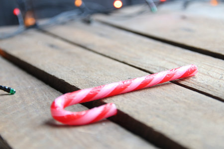 Merry Christmas creative card. Candy cane on a wooden background.