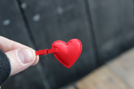 birthday background. A hand holds a red heart on a vintage background.の写真素材
