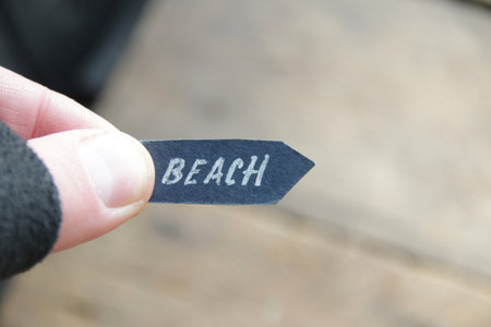 Beach pointer concept. A hand holds a pointer with the inscription beach on a vintage background.の写真素材