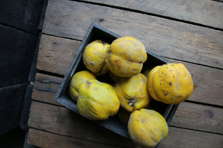 Ripe quince in a box on a vintage wooden table.の写真素材