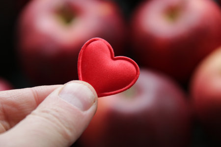 Hand holding a heart on the background of an apple healthy food idea.の写真素材