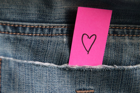 The heart is drawn on the tag in a pocket of blue jeans. Birthday background.の写真素材