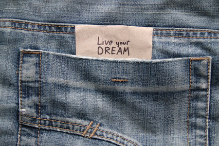 Live your dream concept. Motivational quotes inscription on a tag in a pocket of blue jeans.の写真素材
