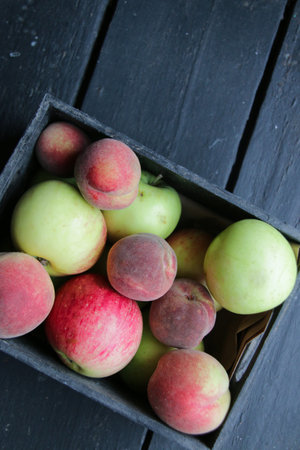 Apples and peaches in a wooden box. top view.の写真素材