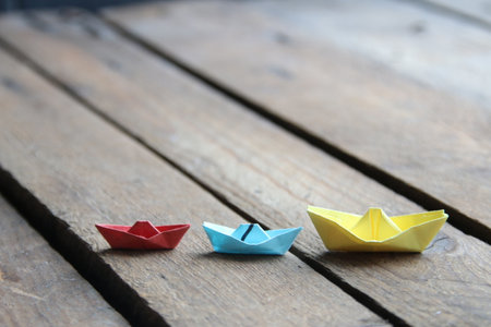 leadership concept. Paper boats on vintage wooden background.の写真素材
