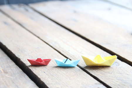leadership concept. Paper boats on vintage wooden background.の写真素材