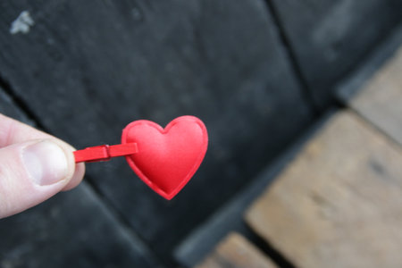 A hand holds a red heart on a vintage background.の写真素材