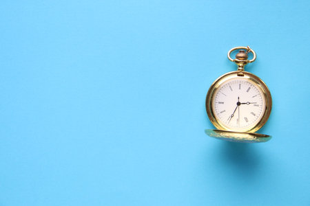 Golden retro pocket watch on a blue background.の写真素材
