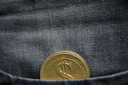 Financial business background. A gold dollar in a jeans pocket.