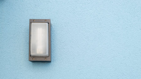 Exterior wall light on the left of a blue wall