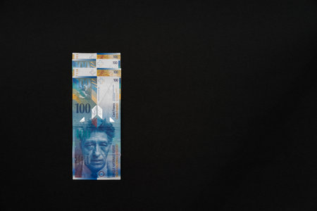 Four banknotes arranged on top of each other front side on top of black background