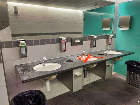 Winterthur, Zurich - Switzerland - May 27, 2020: The middle washbasin is locked and glued with red plastic tape to ensure the distance in the public toilet in the Coop GrÃ¼zemarkt shopping center.のeditorial素材