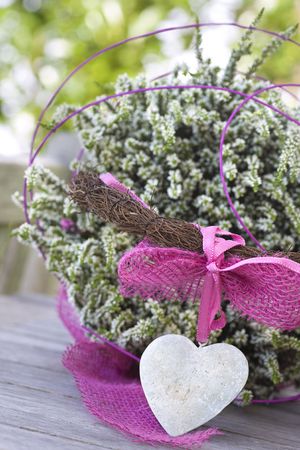 Beautiful basket with a stone heart and heather on a tableの写真素材
