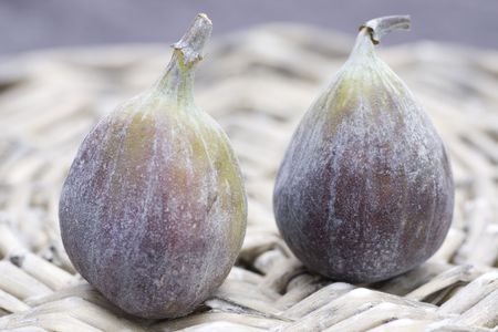 Two fresh figs on wicker plateの写真素材