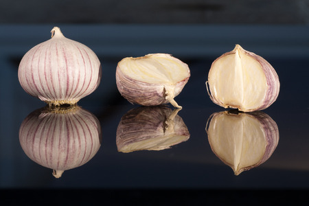 Garlic before glossy dark blue backgroundの写真素材