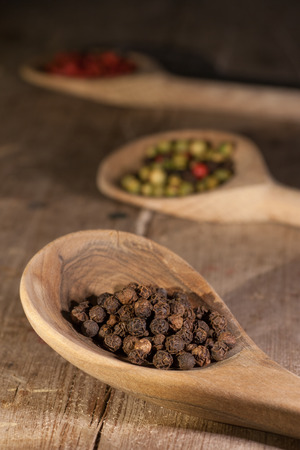 Top view of wooden spoon full of mixed colorful peppercornsの写真素材