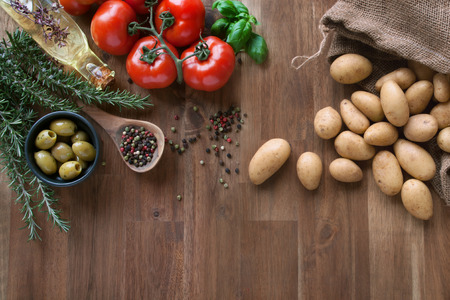 Fresh tomatoes with spices and potatoes on a wooden tableの写真素材