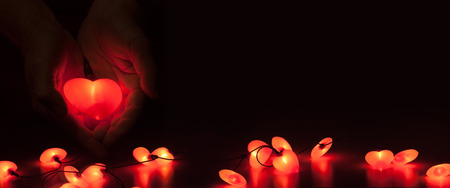 Panorama with glowing heart and loving hands against a dark backgroundの写真素材