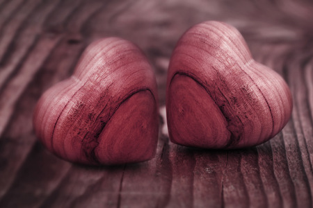Background in pastel red with two hearts of wood for love greetingsの写真素材