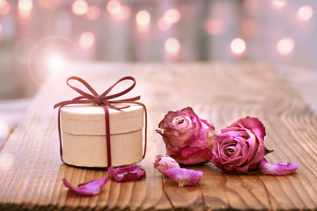 Romantic still life on wood with dried rose blossom and a gift for Mothers Day or Valentines Dayの写真素材