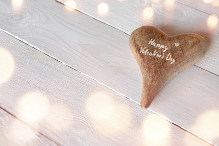 Happy valentines day on a heart with white wooden background and bokehの写真素材