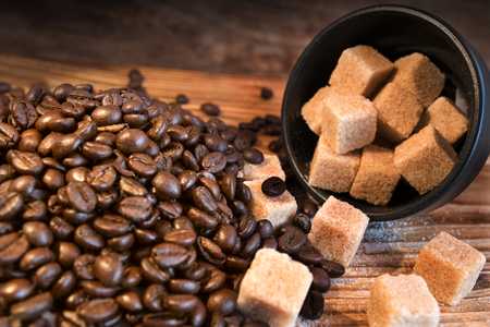 Still life with coffee beans and diced sugar on a wooden tableの写真素材
