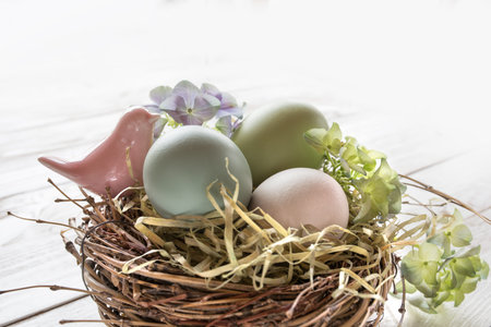 Pastel colored easter eggs with a little pink bird in a nest of straw