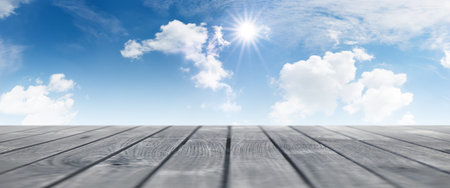 Summer panorama with blue sky clouds and sun with a wooden terraceの写真素材