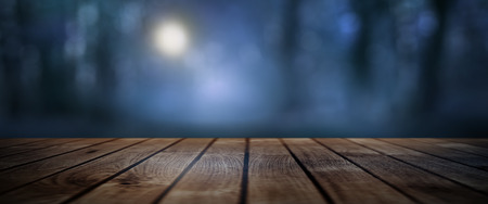 Dark mystical forest with moonlight and rustic wooden floor for a halloween conceptの写真素材