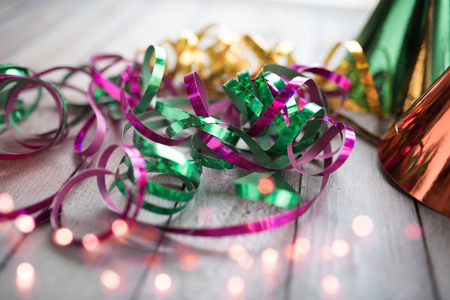 Colorful glittering carnival streamers on a wooden table with pink bokehの写真素材