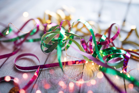 Colorful glittering streamers on wood with light string and pink bokehの写真素材