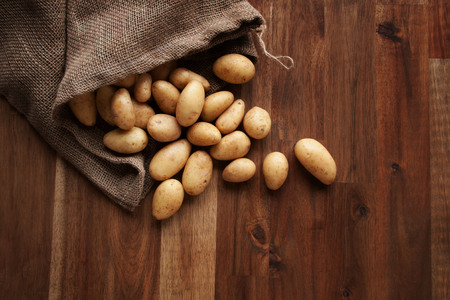 Raw potatoes healthy vegetables on a wooden kitchen tableの写真素材