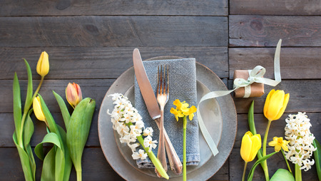 Table decoration on gray wooden boards with spring flowers and a little gift for a mothers day dinner in vintage styleの写真素材