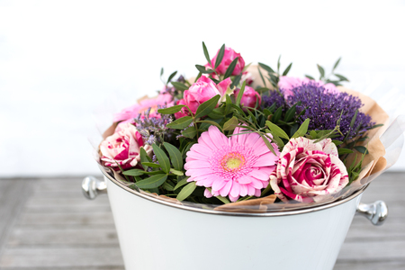 Bouquet of spring flowers in a white vase for mothers day on gray vintage planks and short depth of fieldの写真素材