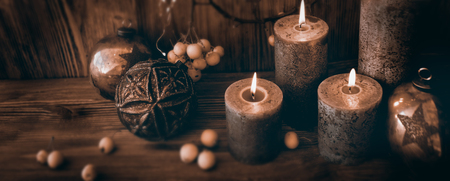 Burning candles with christmas balls decorated on rustic woodの写真素材