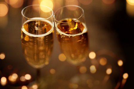 Close up champagne glasses on festive dark background with golden bokehの写真素材