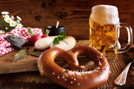 Fresh oktoberfest beer with salt pretzel and white sausage on rustic woodの写真素材