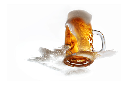 Glass of fresh draft beer with overflowing foam isolatedの写真素材