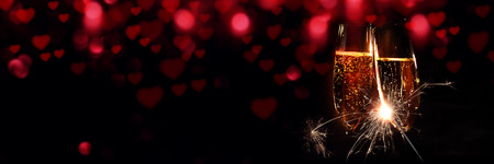 Glasses of champagne with sparkler and red bokeh for valentines dayの写真素材