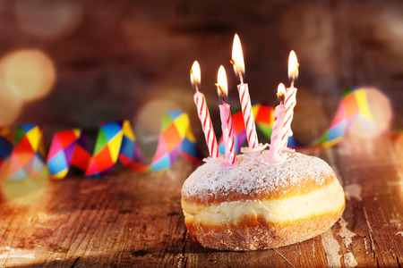 Donut with candles and colorful carnival decoration on rustic woodの写真素材