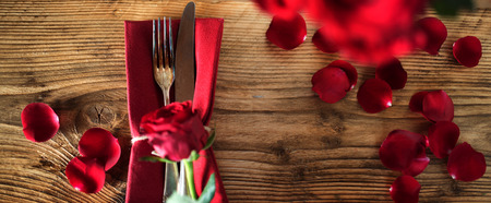 Romantic table decoration with red roses on old wooden table for valentines dayの写真素材