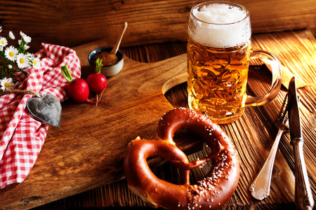 Bavarian specialties with fresh beer and salt pretzel on rustic wood