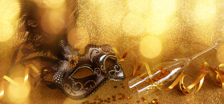 mask with accessories on shiny golden background. Background decoration for traditional mardi gras with space for text and design.の写真素材