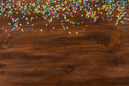 Flat lay photography with colorful confetti on wooden textur. Carnival background. Top view for...