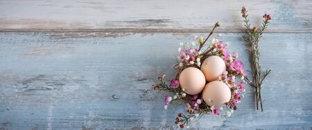 Easter still life with pastel colored eggs on a gray vintage planks. Floral easter decoration. Horizontal flat lay photography with space for text. Top view.の写真素材