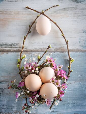 Easter still life with pastel colored eggs on a gray vintage planks. Floral easter decoration. Vertical flat lay photography with space for text. Top view.の写真素材
