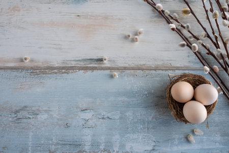 Easter eggs and fluffy willow twigs on gray vintage background. Natural colored eggs in a easter...