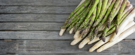 Green and white asparagus on rustic gray wooden planks. Horizontal close-up of vegetables for a healthy nutrition concept with space for text.の写真素材