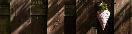 Pink heart with spring flowers at a old wooden fence. Sunny horizontal background for a mothers day...