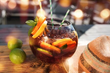 Summer scenery in a bar with fruity fresh sangria. Vacation background with straw hat and golden bokeh. Short depth of field and space for Text.の写真素材